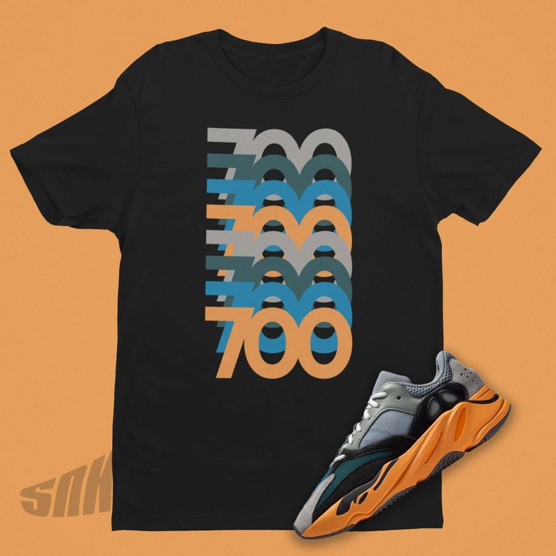May include: Black t-shirt with a graphic of the number 700 repeated in different colors. A pair of orange and grey sneakers with a black sole are in the bottom right corner of the image.