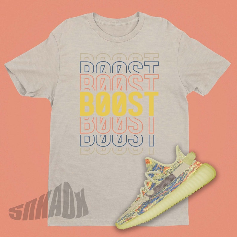 May include: A light grey t-shirt with the word "BOOST" printed in yellow, orange, and blue. The shirt is paired with a pair of yellow and blue sneakers.