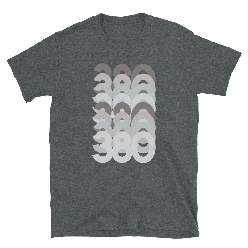 May include: A dark heather grey t-shirt with a graphic design of the number 380 repeated in a layered, faded effect. The numbers are in a light grey color.