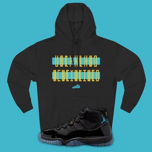 May include: Black hoodie with text in blue and yellow, paired with black and blue sneakers. The sneakers have a glossy finish and a blue sole. The hoodie features a hood and a front pocket. The text on the hoodie is in a stylized font.