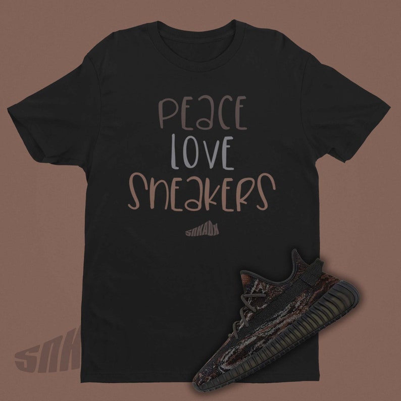 May include: Black t-shirt with the text "peace love sneakers" in brown and gray lettering. A black and brown camouflage sneaker is shown below the text.