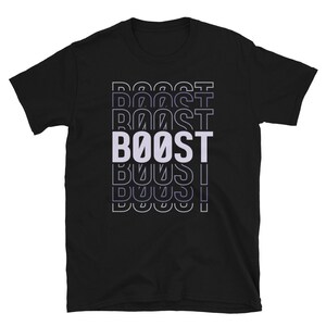 以下が含まれることがあります： 黒のTシャツに、白で「BOOST」と重ねて、積み重ねて、繰り返して書かれたグラフィックデザインが施されています。
