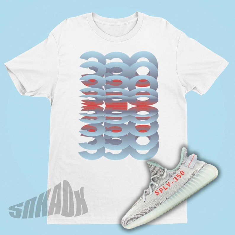 Puede incluir: Camiseta blanca con un dise&ntilde;o abstracto azul y rojo. Un par de zapatillas deportivas grises claras y blancas con el texto rojo "SPLY-350" se muestran junto a la camiseta. El fondo es azul claro.