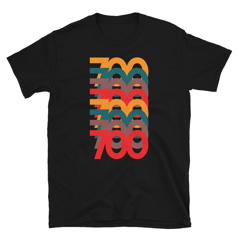 Puede incluir: Camiseta negra con un gr&aacute;fico del n&uacute;mero 700 en un estilo retro superpuesto con colores que incluyen rojo, naranja, amarillo, verde y marr&oacute;n.