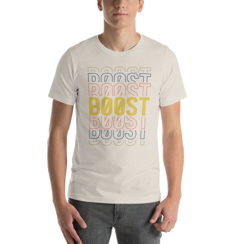 May include: A white t-shirt with a graphic design of the word "BOOST" repeated in different colors and sizes. The word "BOOST" is in yellow, with blue and pink outlines.