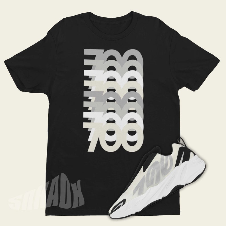 Puede incluir: Camiseta negra con un gr&aacute;fico del n&uacute;mero 700 repetido en diferentes tonos de gris. Tambi&eacute;n se muestra una zapatilla blanca y negra con el n&uacute;mero 700 en el lateral.