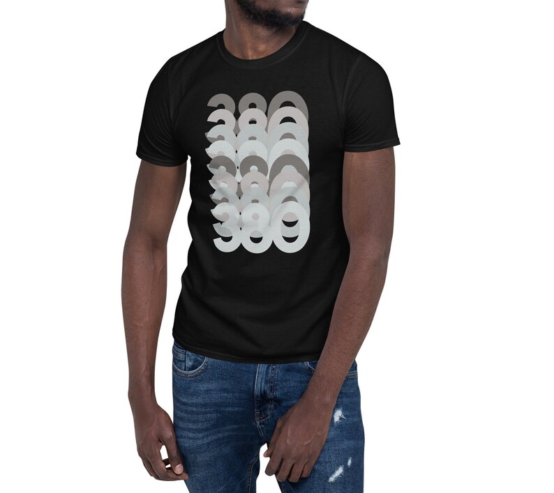 Puede incluir: Camiseta negra con un dise&ntilde;o gr&aacute;fico del n&uacute;mero 380 repetido en un patr&oacute;n superpuesto en capas de diferentes tonos de gris.