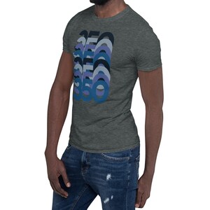 Peut inclure: Un t-shirt gris chin&eacute; avec un motif graphique repr&eacute;sentant le nombre 360 dans un sch&eacute;ma de couleurs bleu, violet et noir.