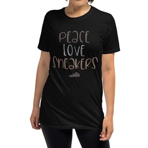 May include: Black short-sleeved t-shirt with the text "Peace Love Sneakers" in brown and white lettering.