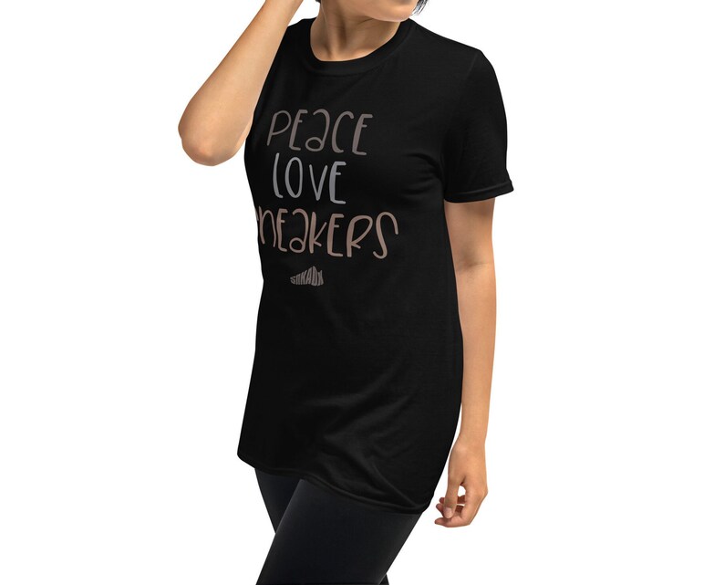 May include: Black t-shirt with the text "Peace Love Sneakers" in a light brown color.