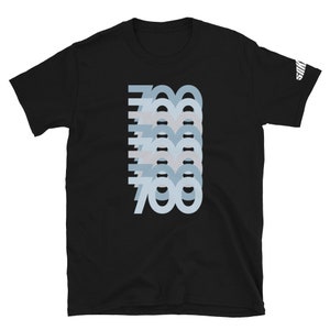Puede incluir: Camiseta negra con un dise&ntilde;o gr&aacute;fico del n&uacute;mero 700 repetido en un patr&oacute;n azul degradado en capas.