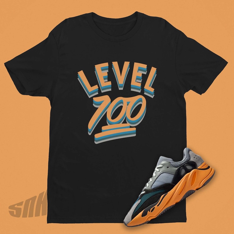Pode incluir: Camiseta preta com o texto "LEVEL 100" em letras laranja e azul. Um par de t&ecirc;nis laranja e cinza com detalhes pretos est&aacute; no canto inferior direito da imagem.