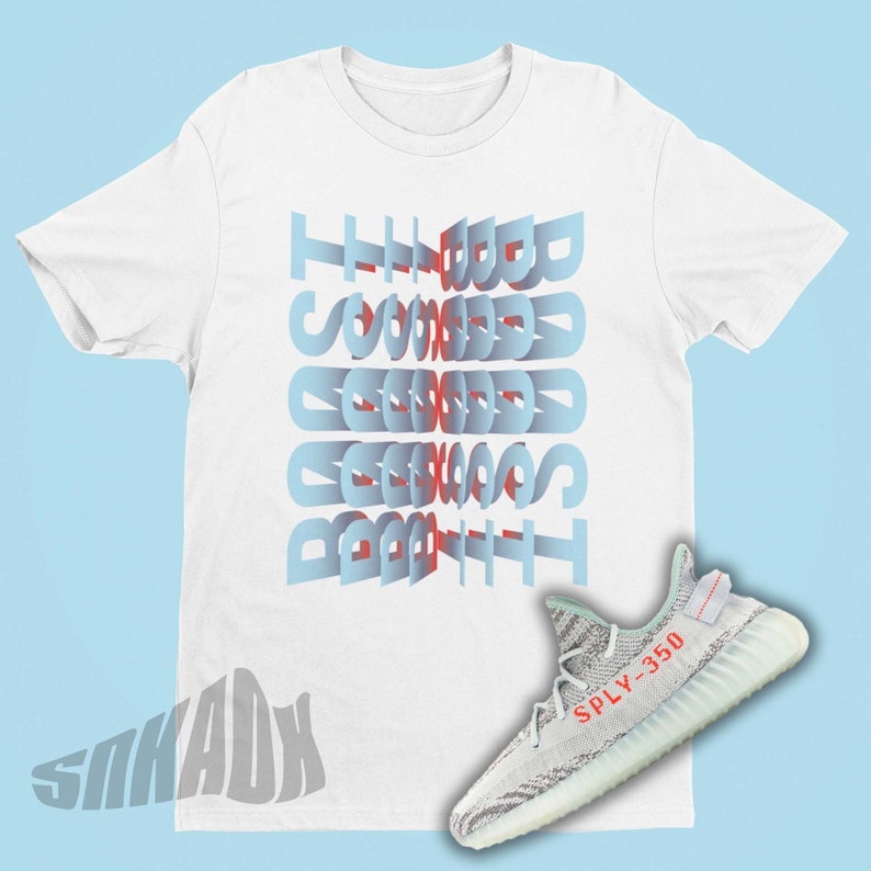 May include: White t-shirt with the text "The Good, The Bad, The Ugly" printed in blue and red. A pair of white and grey sneakers with the text "SPLY-350" printed in red on the side.