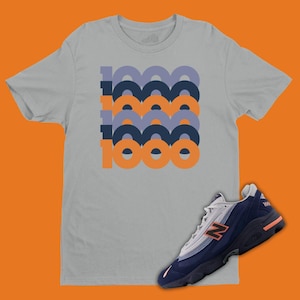 May include: A gray t-shirt with a graphic of the word "1000" in orange and blue. A navy blue and white sneaker with an orange accent is shown below the t-shirt.