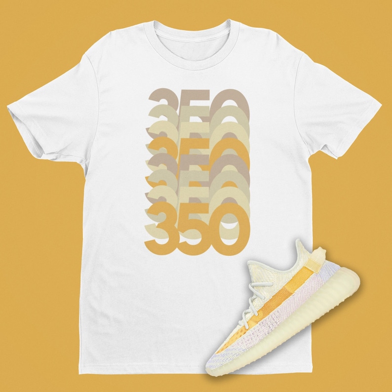 K&ouml;nnte beinhalten: Wei&szlig;es T-Shirt mit einem Aufdruck der Zahl 350, die in einem Retro-Stil wiederholt wird. Ein Paar wei&szlig;er und gelber Sneaker mit einer hellrosa Sohle befindet sich unten rechts im Bild.