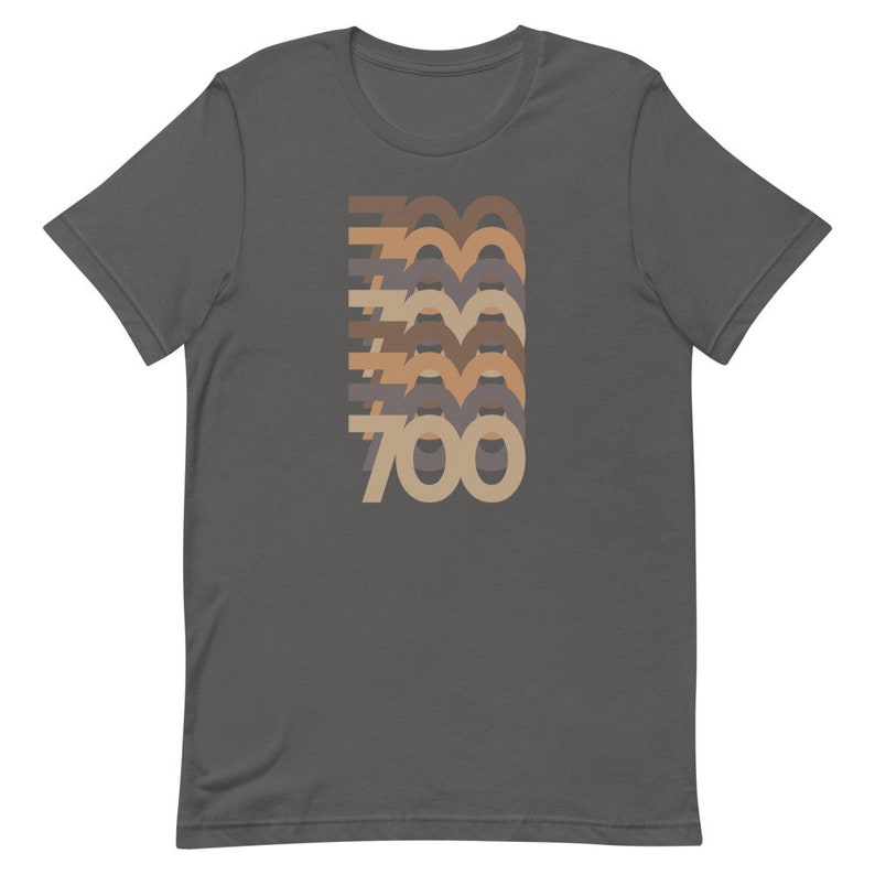 May include: A dark gray t-shirt with a retro-style graphic of the number 700 in different shades of brown, beige, and gray.