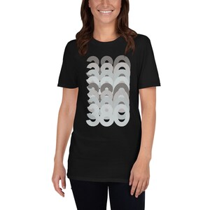 Puede incluir: Camiseta negra con un dise&ntilde;o gr&aacute;fico del n&uacute;mero 380 repetido en un patr&oacute;n superpuesto y descolorido en tonos grises.
