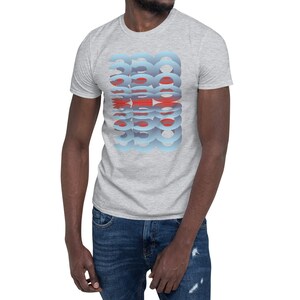 Puede incluir: Una camiseta gris claro con un patr&oacute;n repetitivo de formas azules y rojas. El dise&ntilde;o est&aacute; centrado en la parte delantera. La camiseta tiene mangas cortas y cuello redondo.
