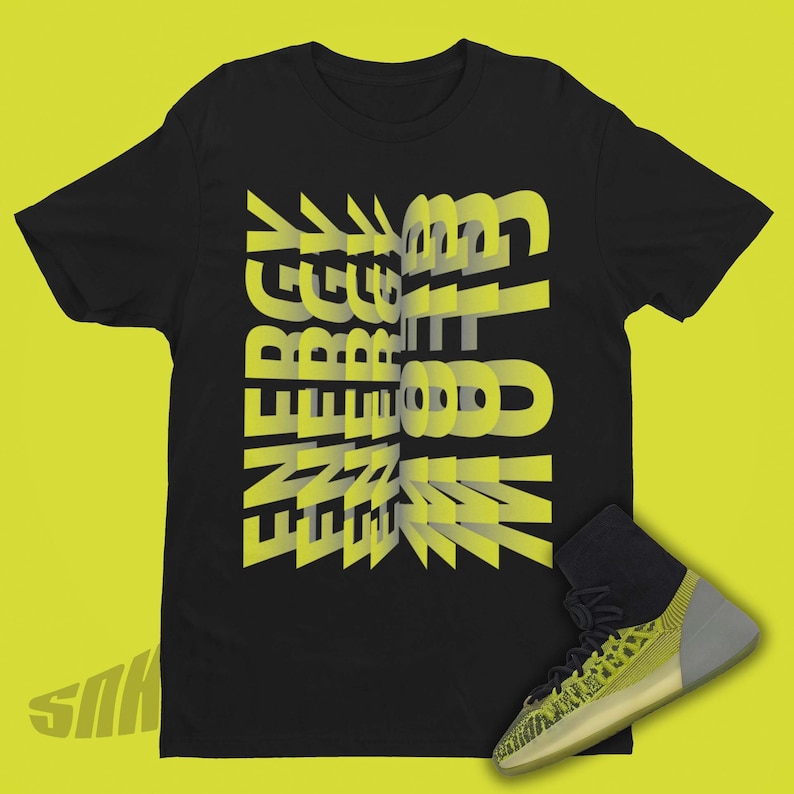 May include: Black t-shirt with a yellow graphic that says "ENERGY" in a 3D style. A yellow and black high-top sneaker is shown below the t-shirt.