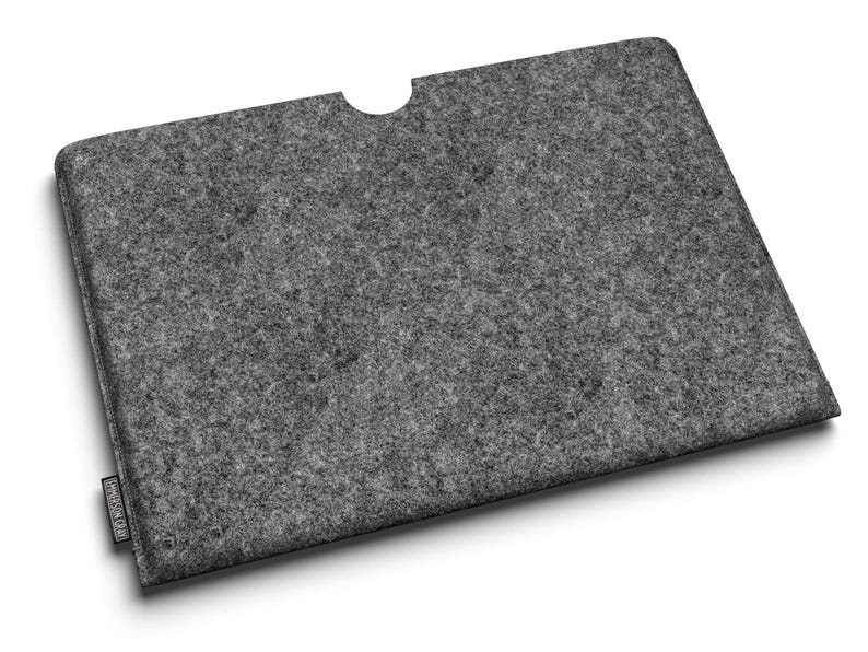 May include: A gray felt laptop sleeve with a curved cutout at the top. The sleeve has a rectangular shape and a textured surface. A small black label is attached to the bottom left corner.