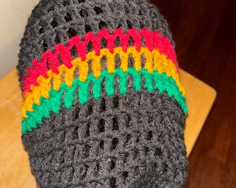 Puede incluir: Un gorro de punto negro con un patrón de rayas rojas, amarillas y verdes.