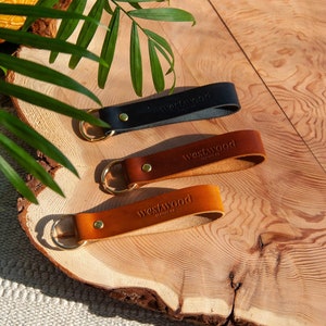 May include: Three leather keyrings with gold key rings. The keyrings are brown, tan, and black. Each keyring has the word "Westwood" embossed on it.