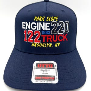 May include: Navy blue baseball cap with embroidered text: "PARK SLOPE ENGINE 220 122 TRUCK BROOKLYN, NY." The cap has a flat brim and a tag that reads "OTTO CLASSIC FIT OSFM MID PROFILE MAXIMUM COMFORT."