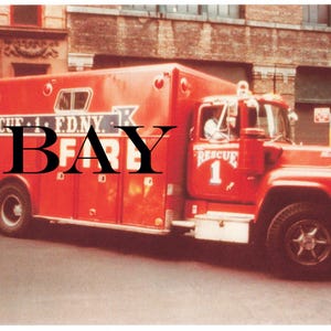 May include: A vintage red fire truck with the text "RESCUE 1 F.D.N.Y. FIRE" and the word "EBAY" in large black letters. The truck is parked on a city street, with buildings in the background.
