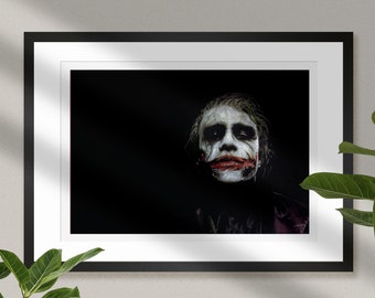 May include: A black and white photo of the Joker from the movie The Dark Knight. He is wearing white face paint with a red smile and has a dark, serious expression.