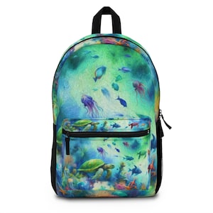 Könnte beinhalten: Ein Rucksack mit einem lebendigen Unterwasser-Design. Das Hauptfach zeigt eine farbenfrohe Illustration von Fischen, Quallen und Meeresschildkröten. Die Vordertasche hat eine kleinere Version desselben Designs mit einem schwarzen Reißverschluss und Trägern.