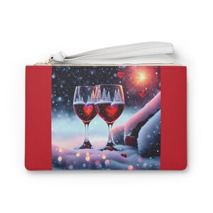 May include: Two wine glasses filled with red wine, with a snowy winter scene in the background. The glasses are decorated with a heart-shaped design and are surrounded by falling snow.