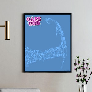 May include: A framed art print featuring a blue background with a light blue, mosaic-style outline of Cape Cod. The words "CAPE COD" are in pink and white bubble letters at the top. The print is displayed on a white wall.