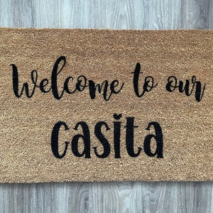 May include: A brown coir doormat with the text "Welcome to our casita" in black cursive lettering.