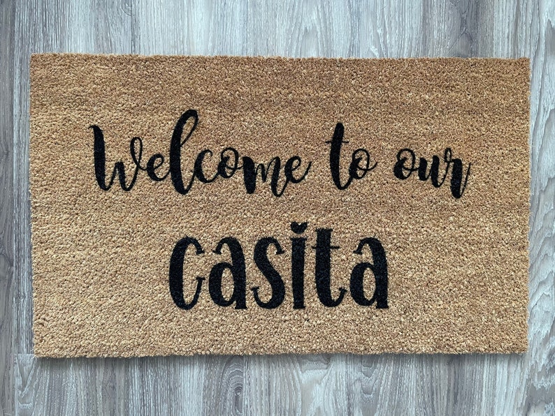 May include: A brown coir doormat with the text "Welcome to our casita" in black cursive lettering.