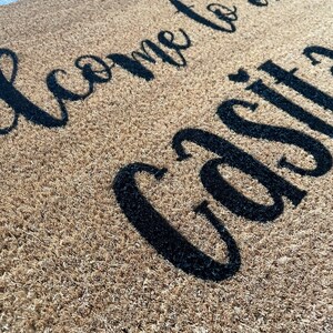 May include: A brown coir doormat with the text "Welcome to our Casita" in black cursive lettering.
