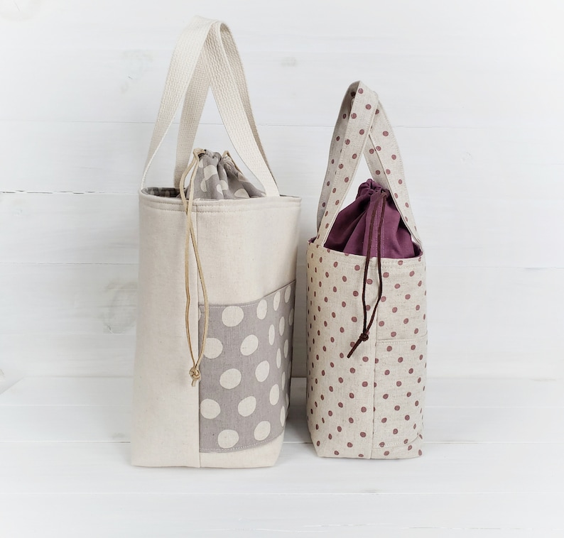 May include: Two tote bags with polka dot patterns. The larger bag is white with gray polka dots and the smaller bag is beige with maroon polka dots.