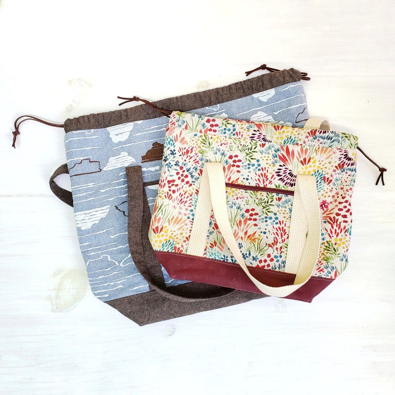 May include: Two fabric tote bags. The smaller bag is brown with a floral print and has a cream-colored strap. The larger bag is blue with a cloud print and has a brown strap.