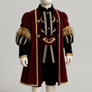 Könnte beinhalten: Ein Kinderkostüm mit einem burgunderfarbenen Samtmantel mit goldenen Verzierungen und Fellakzenten an den Ärmeln. Das Outfit umfasst ein schwarzes Samt-Oberteil mit goldener Stickerei und einen passenden Gürtel, kombiniert mit schwarzen Shorts.