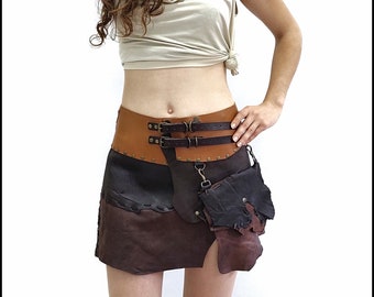Puede incluir: Una falda de cuero marrón con un panel de cuero negro y un cinturón de cuero marrón con dos hebillas y una cadena de metal. La falda tiene varios bolsillos y correas.