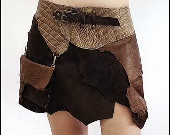 Puede incluir: Una falda de cuero marrón con un cinturón marrón y beige con estampado de cocodrilo. La falda tiene un bolsillo con solapa en el lado izquierdo y un bolsillo grande con solapa en el lado derecho.