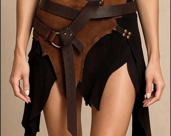 May include: A layered skirt featuring a black fabric base with an asymmetrical hemline and an overlay of brown suede-like material. The brown section is secured with a dark brown leather-style belt, a circular metal ring, and metallic studs.
