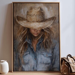 May include: A framed painting of a person wearing a cowboy hat and denim shirt. The artwork has a neutral color palette with a focus on the subject's face and long hair. The painting is displayed above a wooden bench with vases and a bag.
