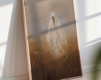 May include: Framed artwork depicting a hooded figure in a field of tall grass. The artwork has a muted color palette of browns, tans, and grays. The frame is a light brown color. The artwork is leaning against a white wall.