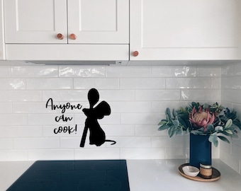 May include: A black silhouette of a mouse holding a wooden spoon with the text "Anyone can cook!" on a white tiled kitchen backsplash.