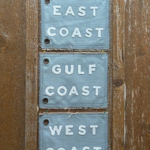 May include: Three blue fabric patches with white embroidered text. The top patch reads "EAST COAST", the middle patch reads "GULF COAST", and the bottom patch reads "WEST COAST".