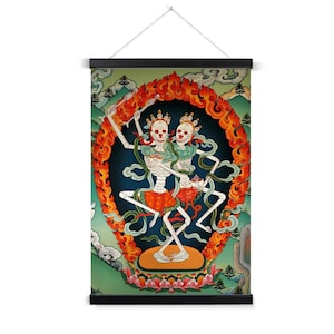 May include: A wall hanging featuring a vibrant illustration of two skeletons dancing within a fiery orange and red halo. The skeletons wear crowns and colorful clothing, set against a backdrop of mountains and clouds. The artwork is framed with a black wooden bar.