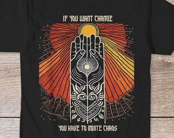 May include: Black t-shirt with a graphic design of a hand reaching towards a sun with the text "If you want change you have to invite chaos".