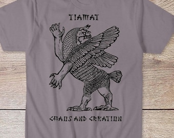 May include: A grey t-shirt featuring a black graphic of a winged creature with the text "TIAMAT CHAOS AND CREATION" printed on the front.