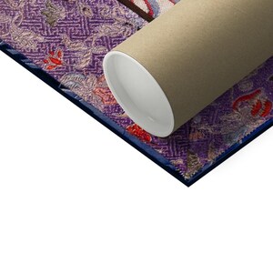 Pode incluir: Um close-up de uma impress&atilde;o em tela enrolada com um tubo de papel&atilde;o marrom. A impress&atilde;o em tela apresenta um design estampado em roxo e azul com detalhes em vermelho e branco.