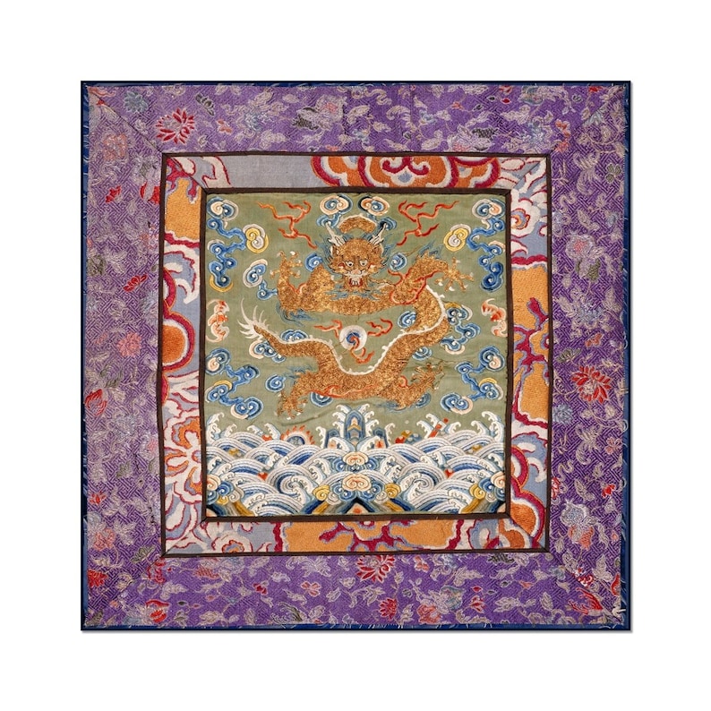 Pode incluir: Uma tape&ccedil;aria bordada quadrada com um drag&atilde;o dourado sobre um fundo verde. O drag&atilde;o &eacute; cercado por nuvens e ondas. A tape&ccedil;aria &eacute; emoldurada com uma borda roxa e dourada.